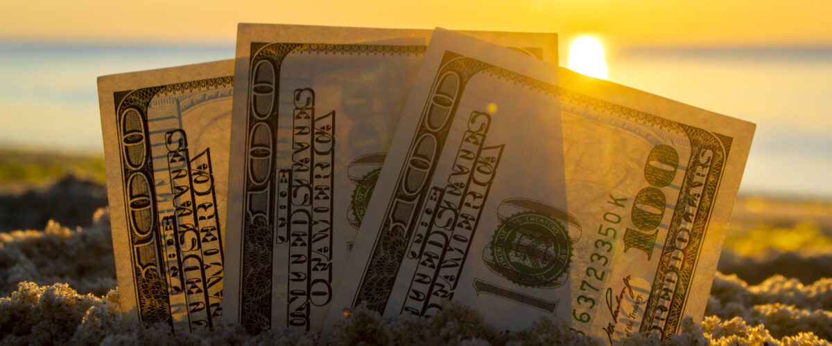 Three dollar bills are buried in sand on sandy beach near sea at sunset dawn in summer close-up. Money grows in sand. Dollars buried in ground. Growing money in sand. One hundred dollar bill money.
