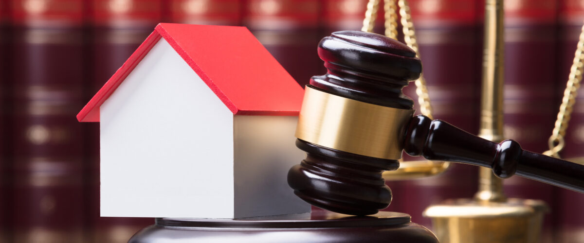 Close-up Of Gavel And House Model On Sounding Block