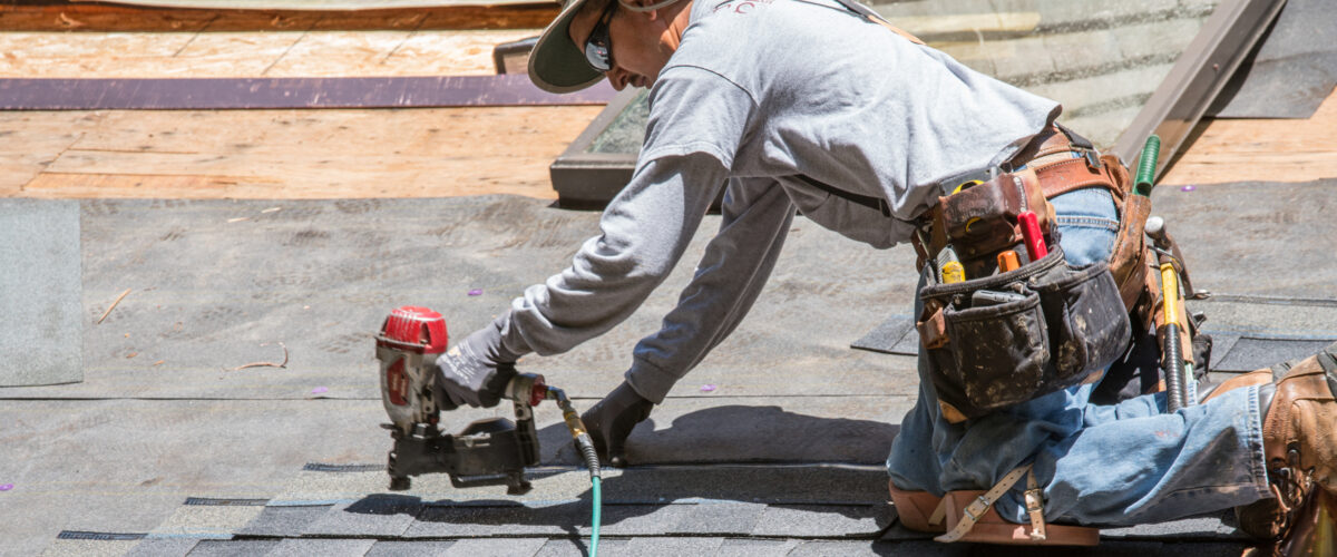 Installing new roof with  nail gun and shingles