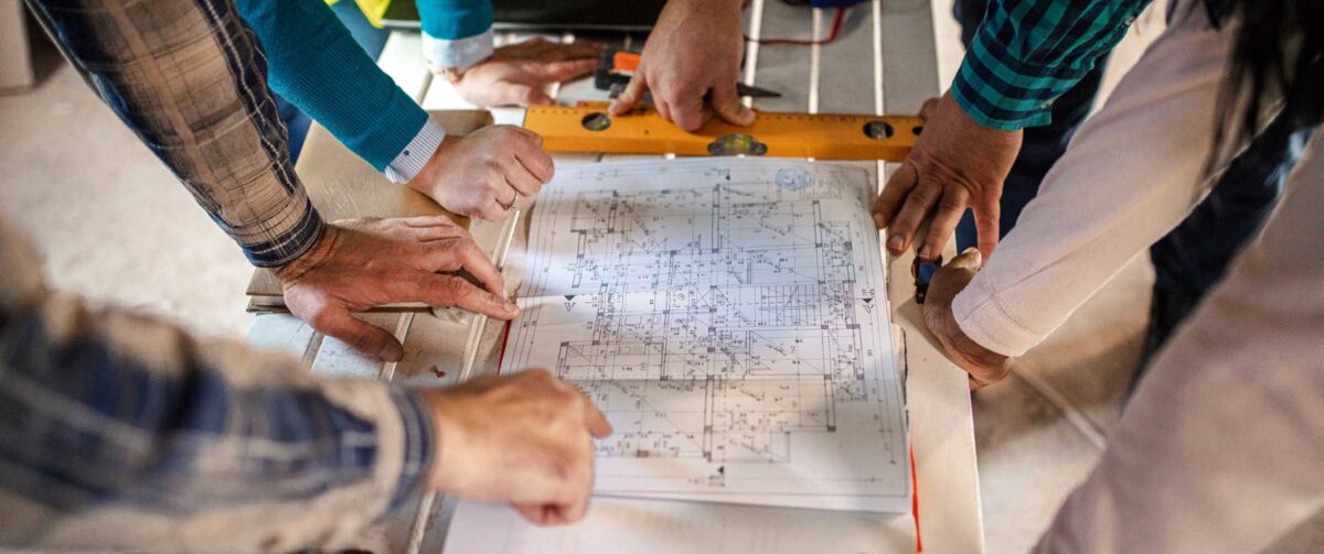 Engineers and architects looking at building blueprint at the construction site