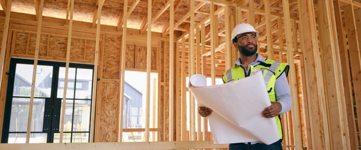A construction worker inspecting a home under construction.